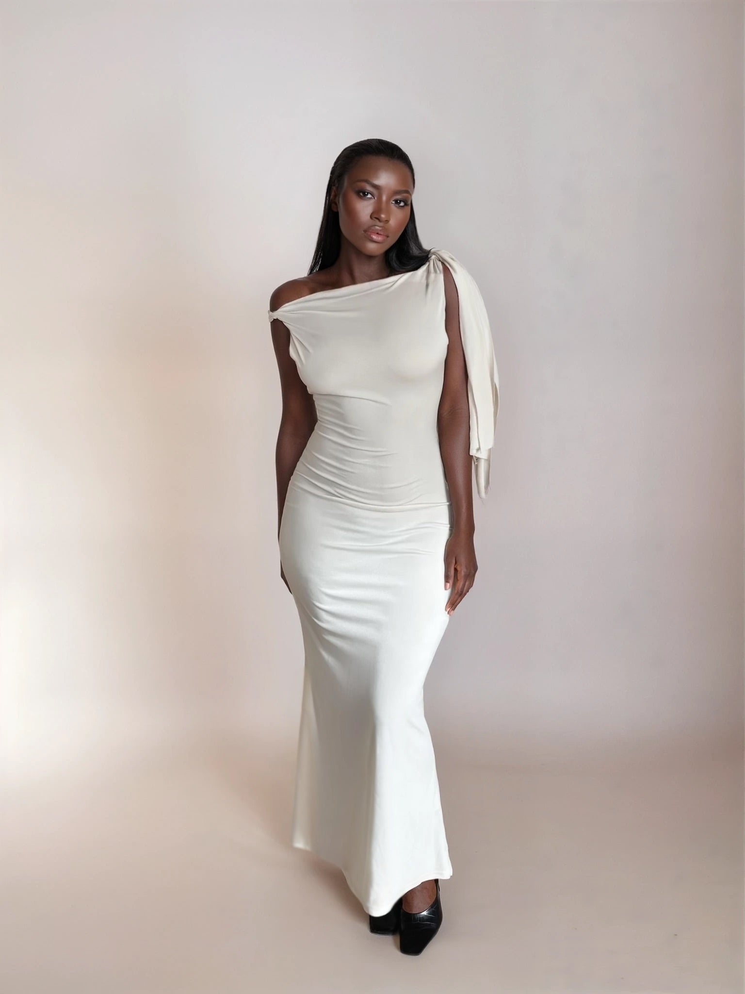Woman wearing a white one-shoulder dress against a plain background